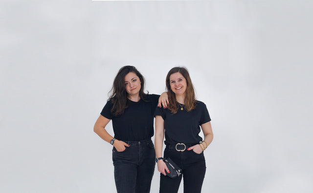 Photo studio de Marion Xerri et Domitille Pescia, les deux femmes vêtue de noir souriant à la caméra. Domitille, tient dans sa main une poche noir en cuir vegan de raisin, viahero.