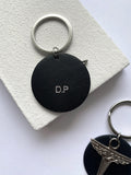Porte clé personnalisé avec les initiales D.P et logo aviateur phénix en métal argenté, rond de cuir vegan en raisin rouge, fabriqué en france